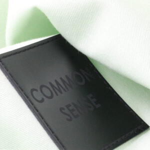 Black logo patch detail applied to light garment fabric